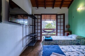 A room with two beds, a hammock, a wooden staircase, and a view of greenery outside. - Casa com fogão a lenha para 7 | Vale das Videiras (Itaipava, Petropolis)