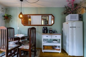 Eine kleine Küche mit Esstisch, Stühlen, Kühlschrank, Kaffeemaschine und Mikrowelle.