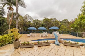 Ein Poolbereich mit Liegestühlen, Sonnenschirmen und Topfpflanzen.
