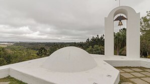 Uma igreja branca com uma torre de sino e uma estrutura em formato de cúpula em primeiro plano.