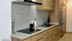 A modern kitchen with wooden cabinets, a stainless steel refrigerator, and a black countertop.