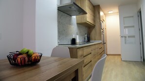 A modern kitchen with wooden cabinets, a marble countertop, and a fruit bowl on the table.