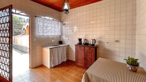 A compact kitchen with a window, a sink, a cabinet, and a table with a plant. - Casa c garagem, wi-fi, Pet Friendly, prox Capivari (Campos do Jordão)