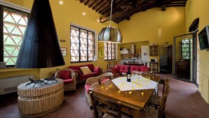 A spacious living area with a high ceiling, a large chimney, and a dining table set for two. - The Colletalli Barn (Radicondoli)