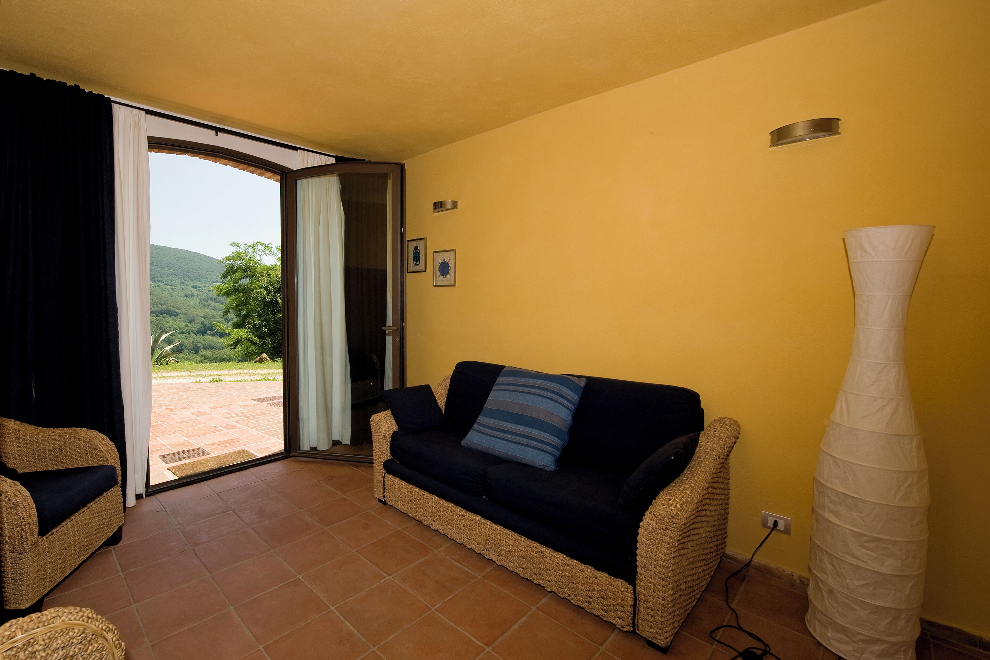 Un salón con sofá, lámpara y vistas al balcón por un ventanal.