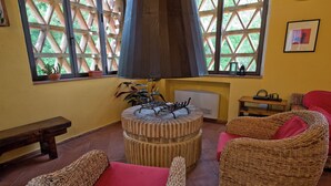 A cozy room with wicker furniture, a round table, and a fireplace. - The Colletalli Barn (Radicondoli)
