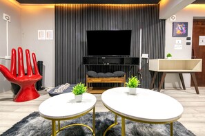 A modern living room with a flat-screen TV, two white round tables, a red chair, a sofa, and a wooden bench. - Loft retro totalmente equipado en Polanco (Mexico City)