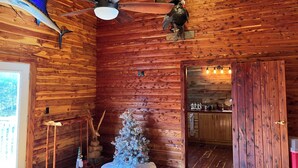Ein Holzblockhaus-Interieur mit Deckenventilator, Weihnachtsbaum und einer rustikalen Küchenzeile.