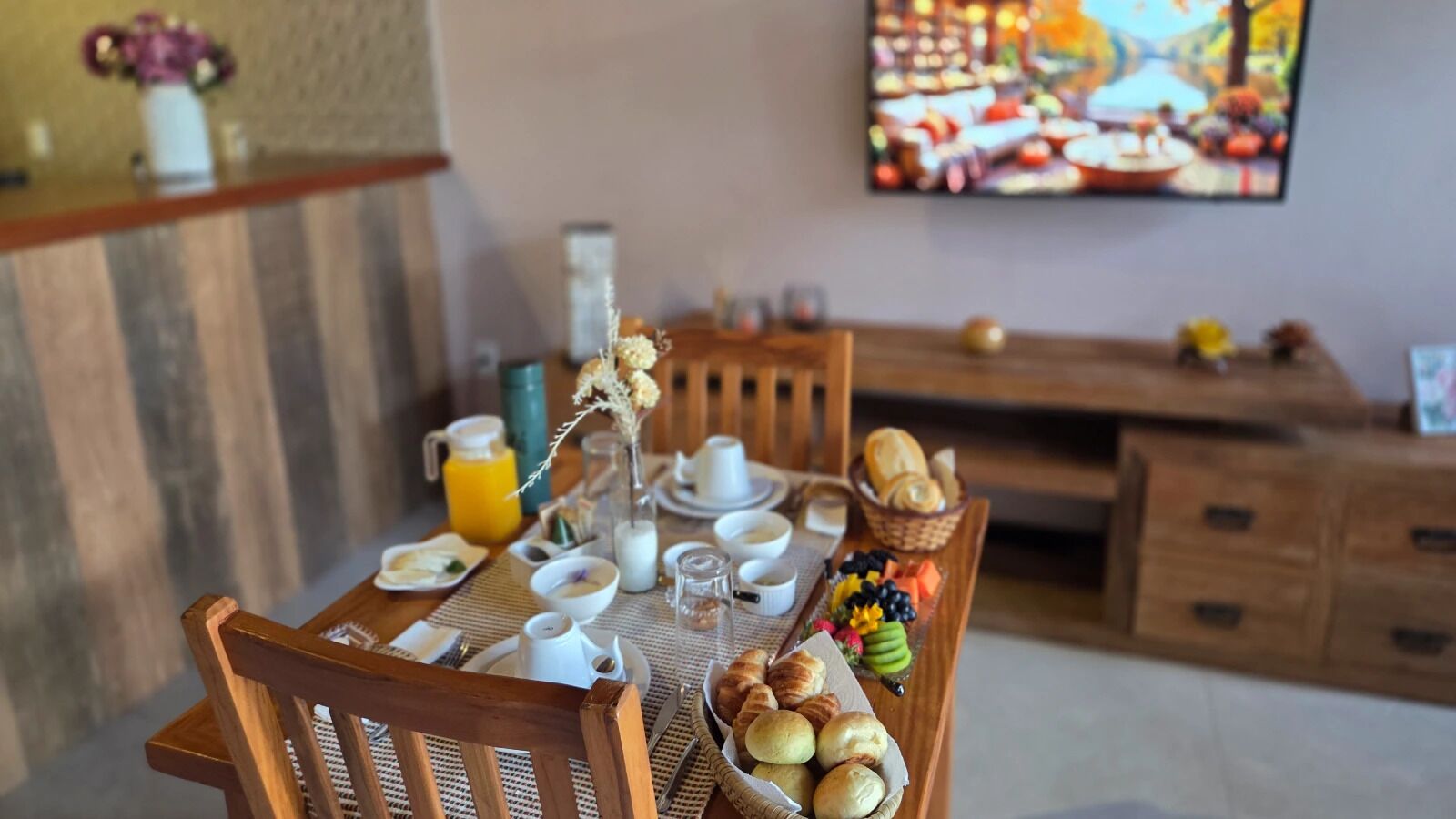 A breakfast setup with a table, chairs, and a TV in the background.