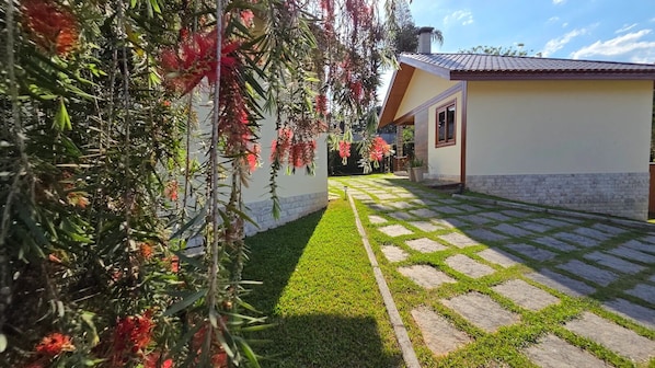 A pathway leading to a building with a tiled roof and a stone wall. - Chalés Renovo Visconde de Mauá (Resende)