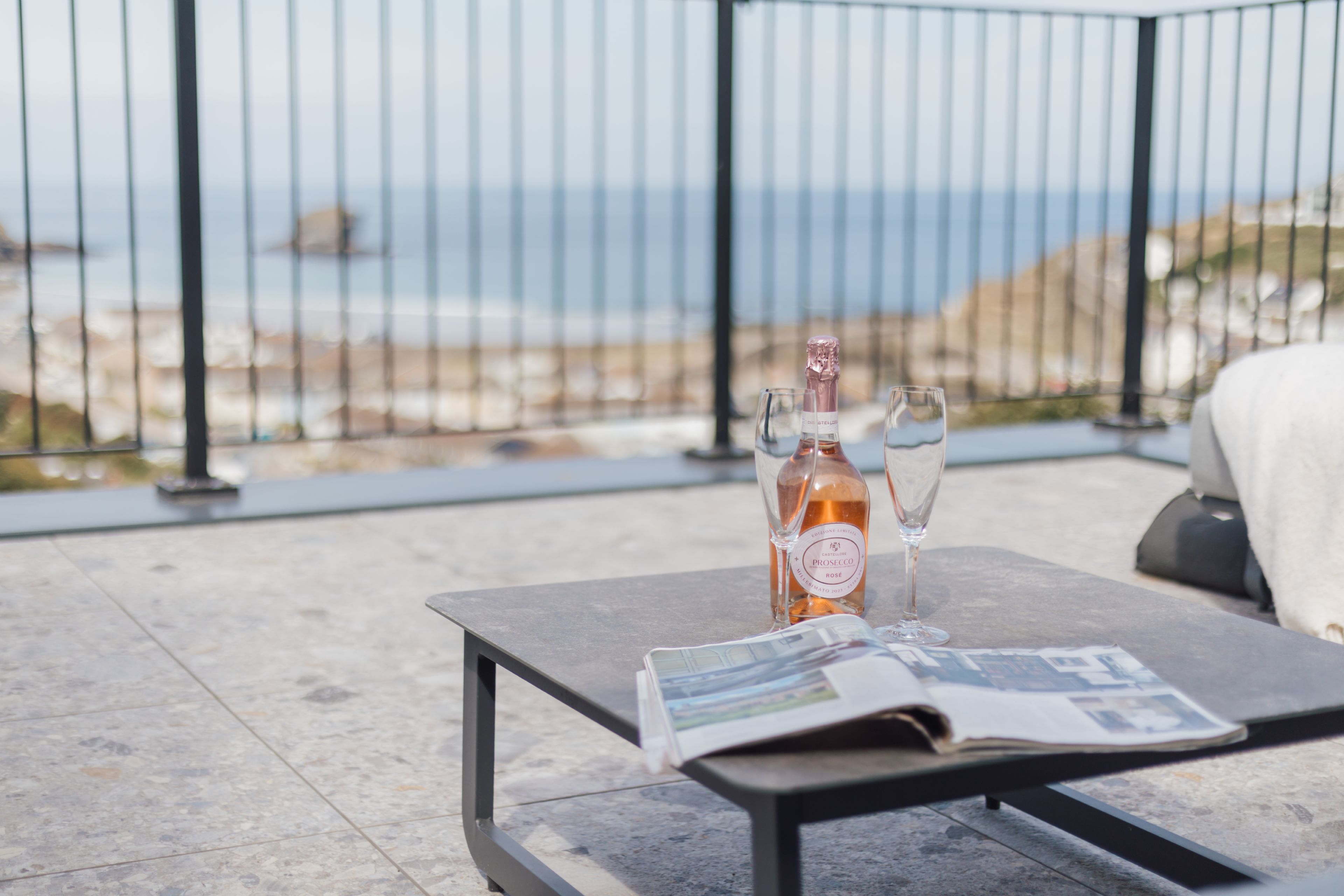 Ein Tisch mit einer Flasche und Gläsern auf einer Terrasse mit Meerblick.