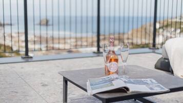 Ein Tisch mit einer Flasche und Gläsern auf einer Terrasse mit Meerblick.