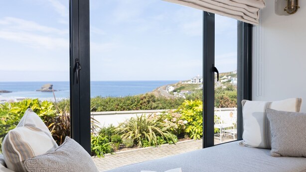 A balcony with a view of the sea and a book on a cushion. - Stunning & Luxurious Family Home Overlooking The Beach With Hot Tub (Portreath)