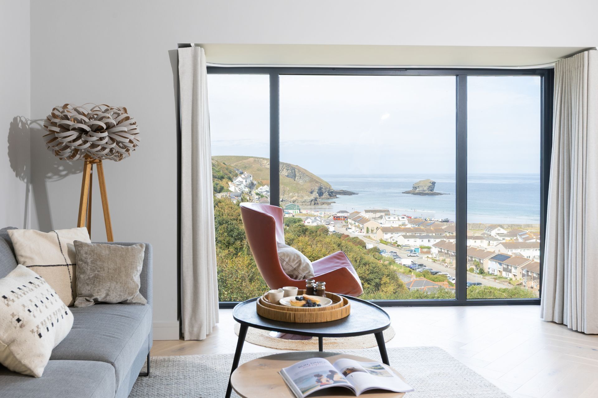 A modern living room with a large window overlooking a coastal town.
