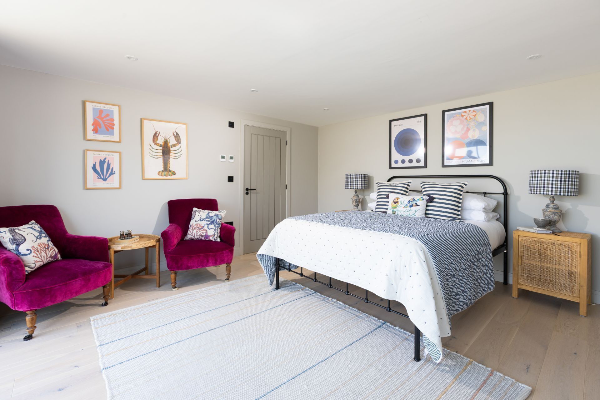 A bedroom with a bed, a chair, a small table, and a nightstand.