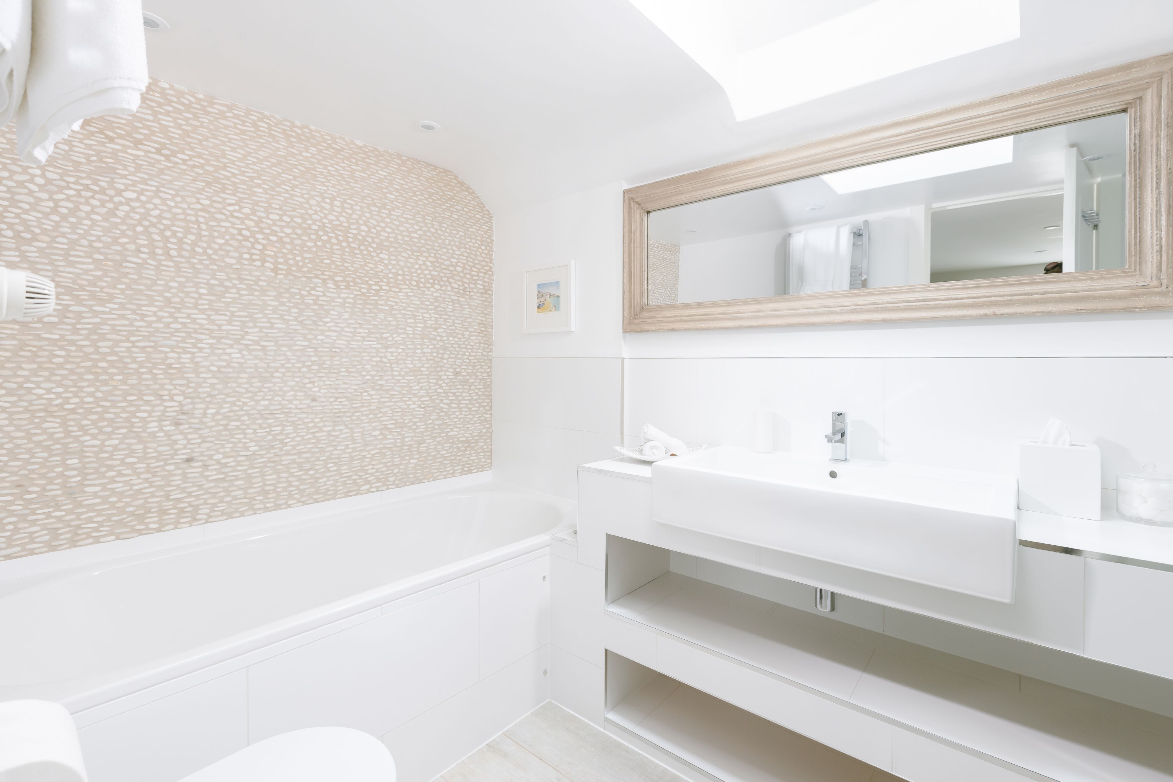 A modern bathroom with a bathtub, a large mirror, and a white vanity.