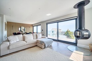 A modern living room with a sectional sofa, large windows, and a fireplace.