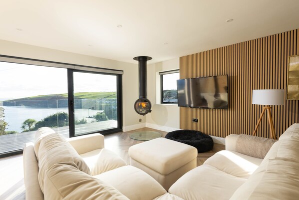 Un salon moderne doté d’une grande fenêtre, d’une cheminée, d’un téléviseur à écran plat et d’un mur décoratif en bois.
