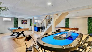 Ein Billardtisch mit Stühlen, ein zweiter Billardtisch, eine Treppe und eine grüne Wand.