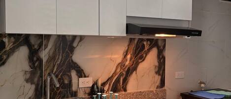 A modern kitchen with white cabinets, a marble backsplash, and a gas stove.