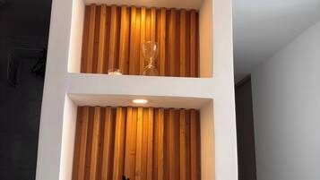 Un interior moderno con encimera de mármol, listones de madera en la pared y una lámpara colgante.