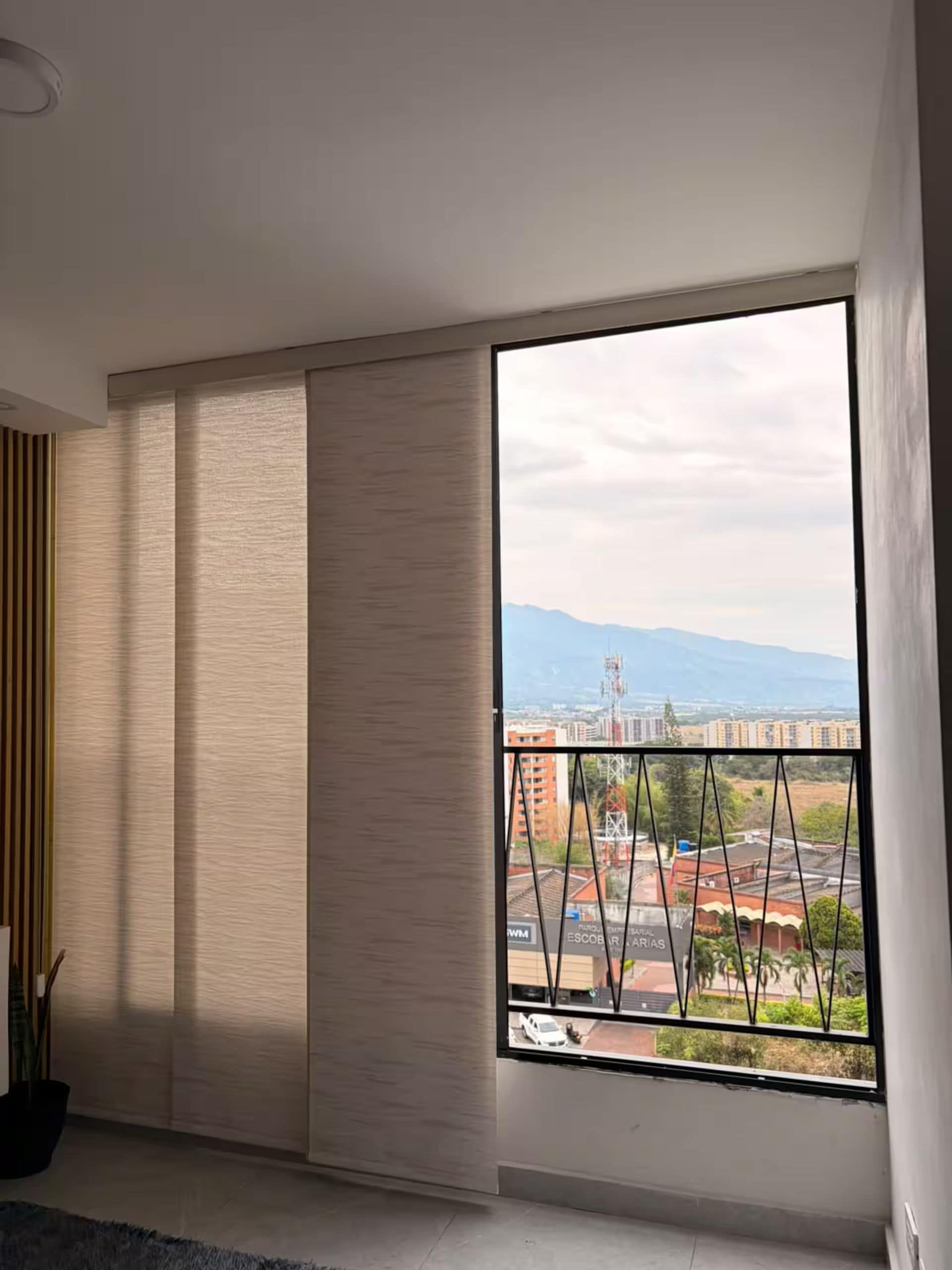 Habitació amb finestra gran, porta corredissa i vista a la ciutat.