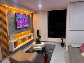 Una sala de estar moderna con un televisor de pantalla plana, un sofá, una mesa de centro y un violín.