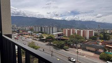 Eine Stadtansicht mit Wolkenkratzern, einer belebten Straße und Bergen im Hintergrund.