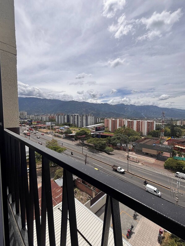 A cityscape with high-rise buildings, a busy street, and mountains in the background. - Apto Premium Ibagué lujoso y moderno (Ibague)
