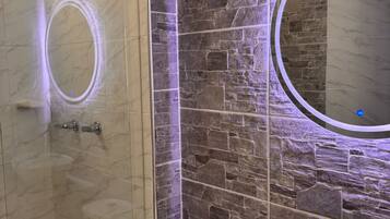 Un baño con cabina de ducha de vidrio, inodoro y tocador con lavamanos.
