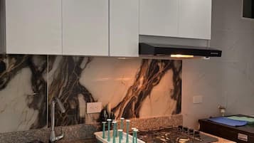 A modern kitchen with a granite countertop, stainless steel sink, and a gas stove.