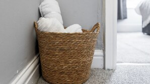 Una cesta tejida con toallas blancas junto a una pared.