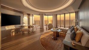 Un vaste espace de vie doté d’un grand téléviseur à écran plat, de sièges confortables et offrant une vue sur le coucher de soleil grâce à de grandes fenêtres.