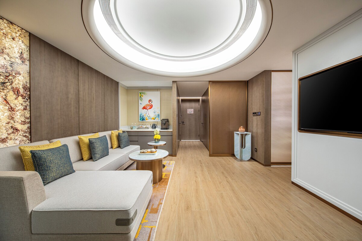 Een moderne hotelkamer met een bank, salontafel en een flatscreen televisie.