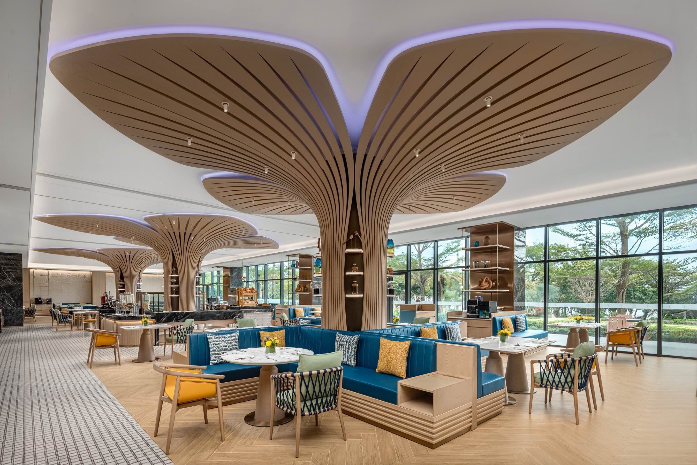 A spacious lobby with modern furniture, large windows, and unique ceiling design.