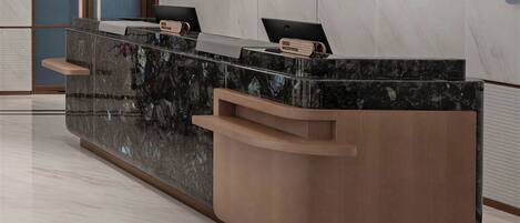 A reception desk with a marble top and wooden base, equipped with two laptops and a decorative item.