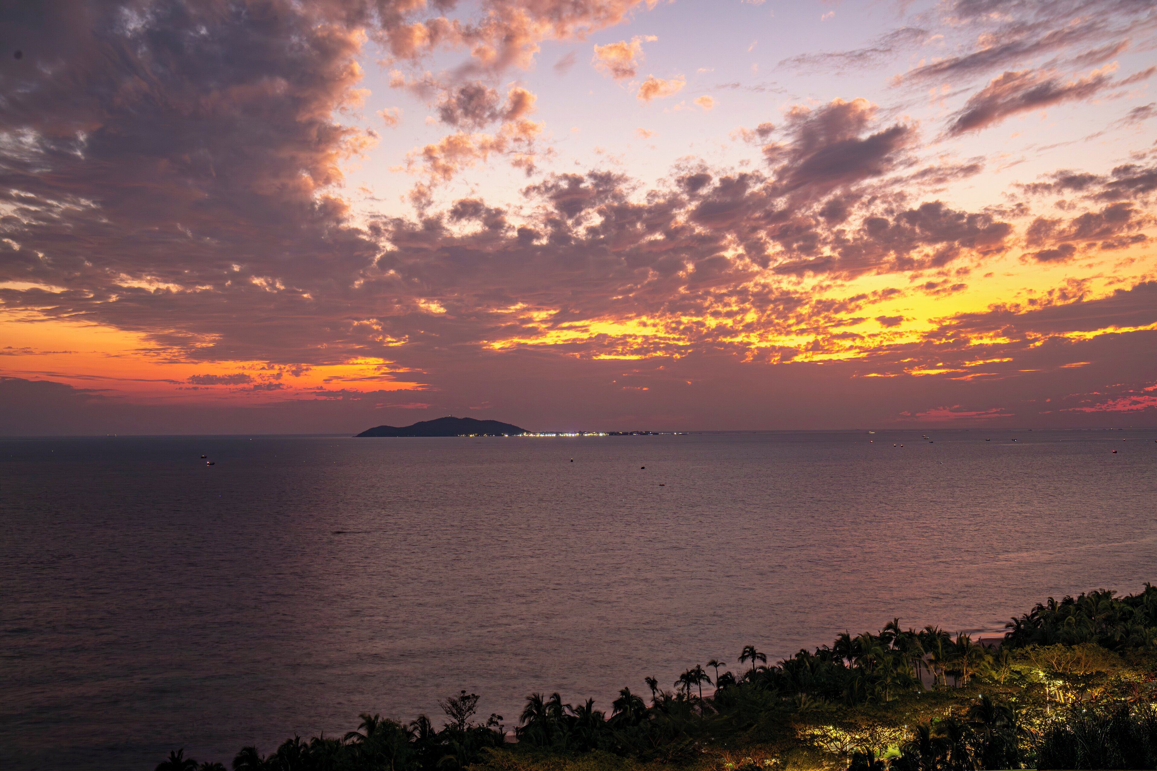 A coastal sunset view with a distant island and calm sea.