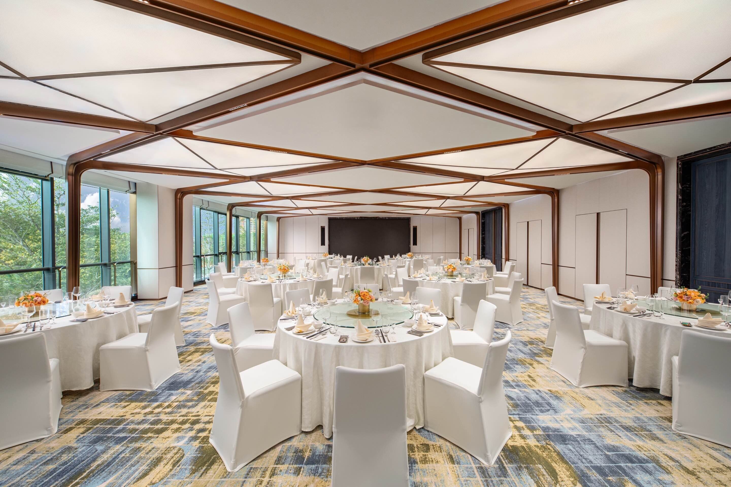 A conference room with round tables, white chairs, and a large screen.