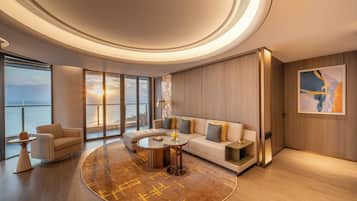 Una sala de estar moderna con un tapete circular, un sofá, una mesa de centro y vista al mar a través de amplios ventanales.