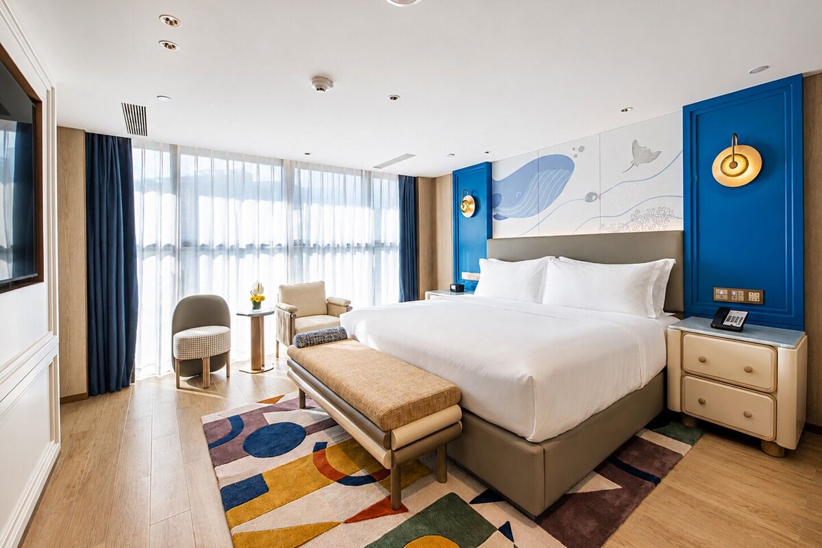 Een hotelkamer met een groot bed, nachtkastjes, een bureau en een stoel.