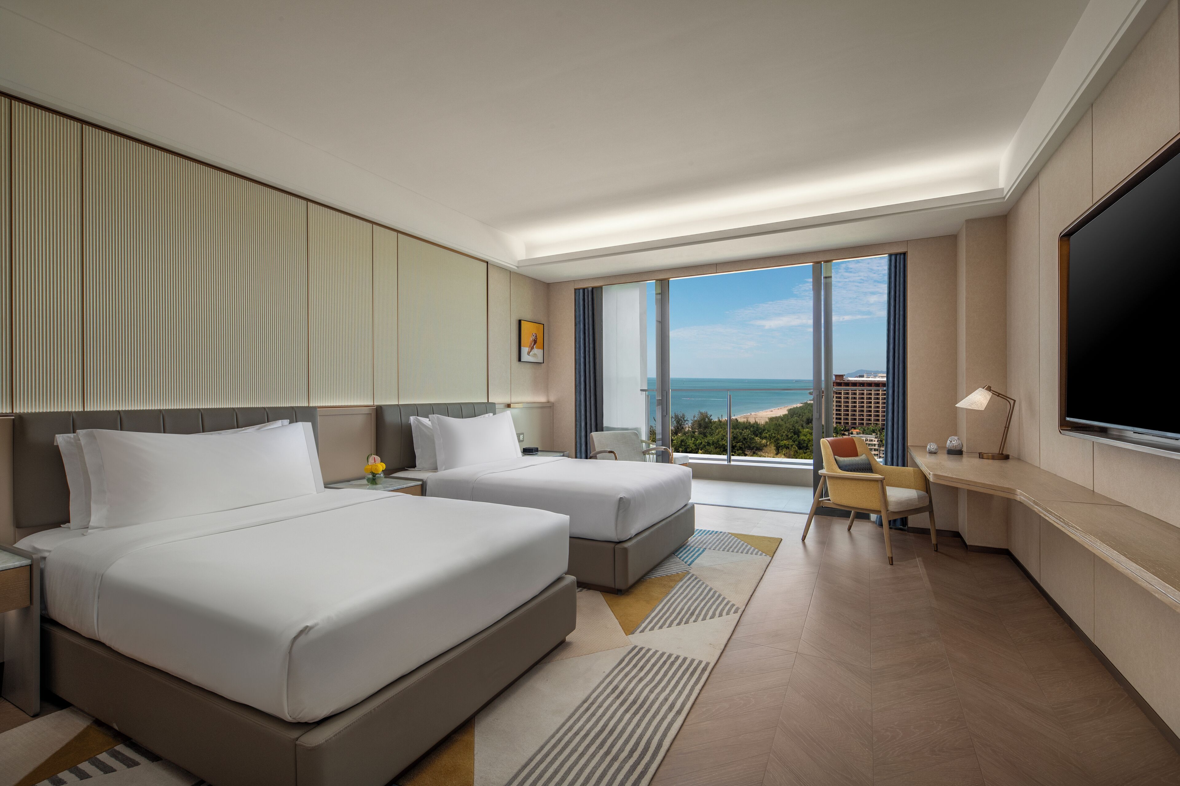 Une chambre d’hôtel moderne équipée de deux lits, d’un bureau, d’une chaise et d’un grand téléviseur.