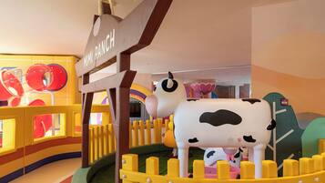 Zona de juegos infantiles con una estructura de juego con forma de vaca y un letrero que dice "Mimi Ranch".