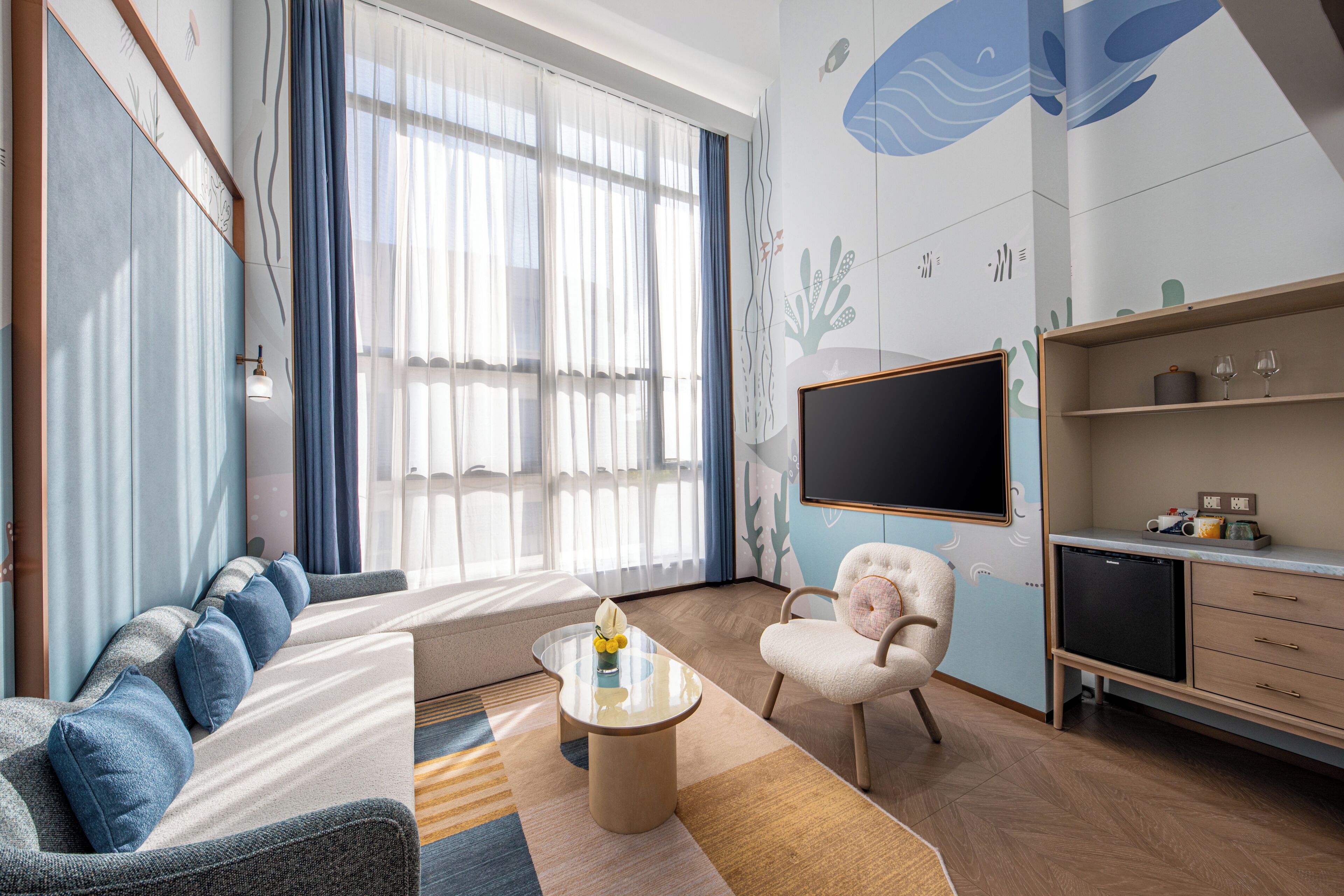 Un salon moderne comprenant un canapé, un fauteuil, une table basse et un téléviseur à écran plat.