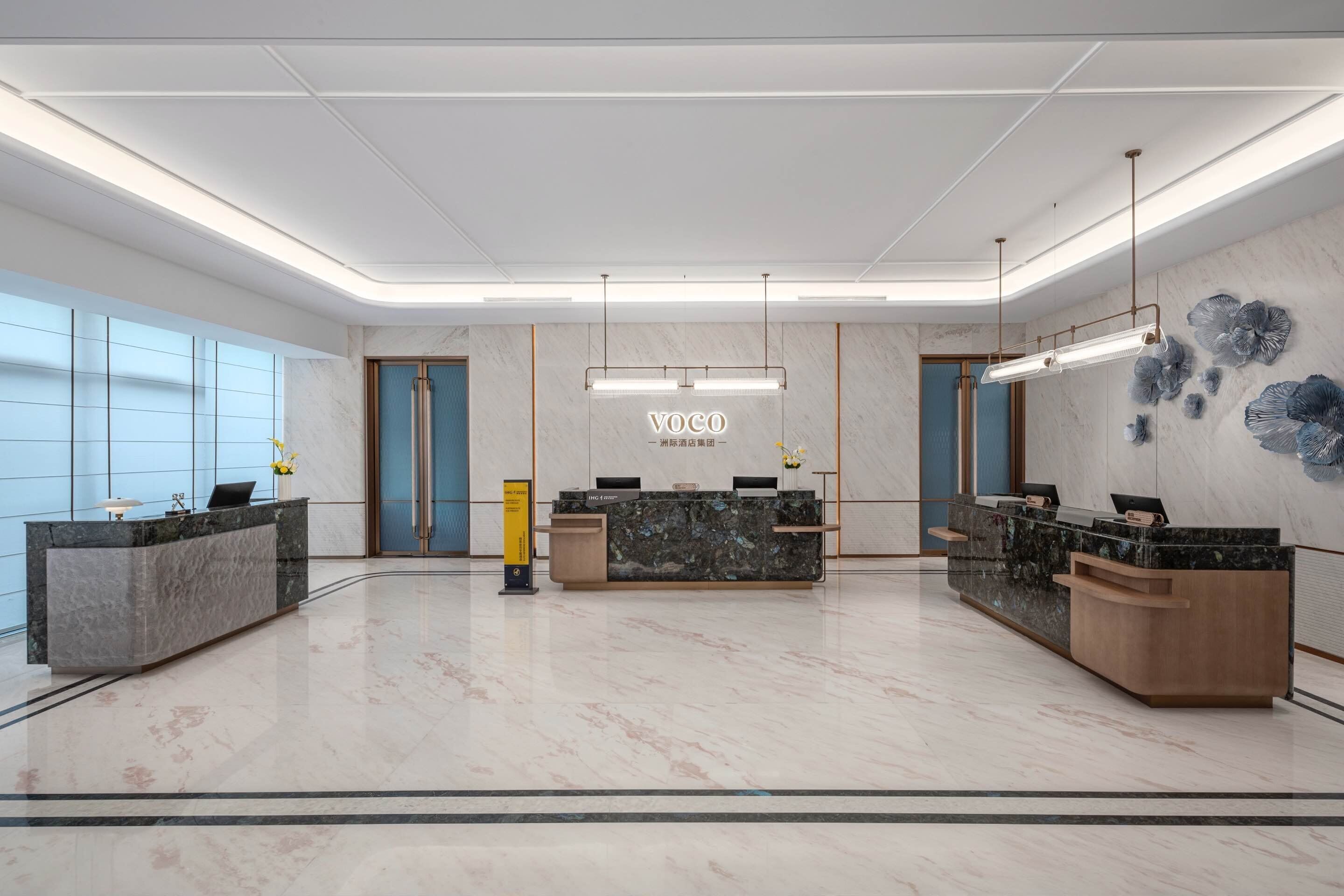 A modern reception area with marble flooring, multiple reception desks, and a large wall-mounted sign.
