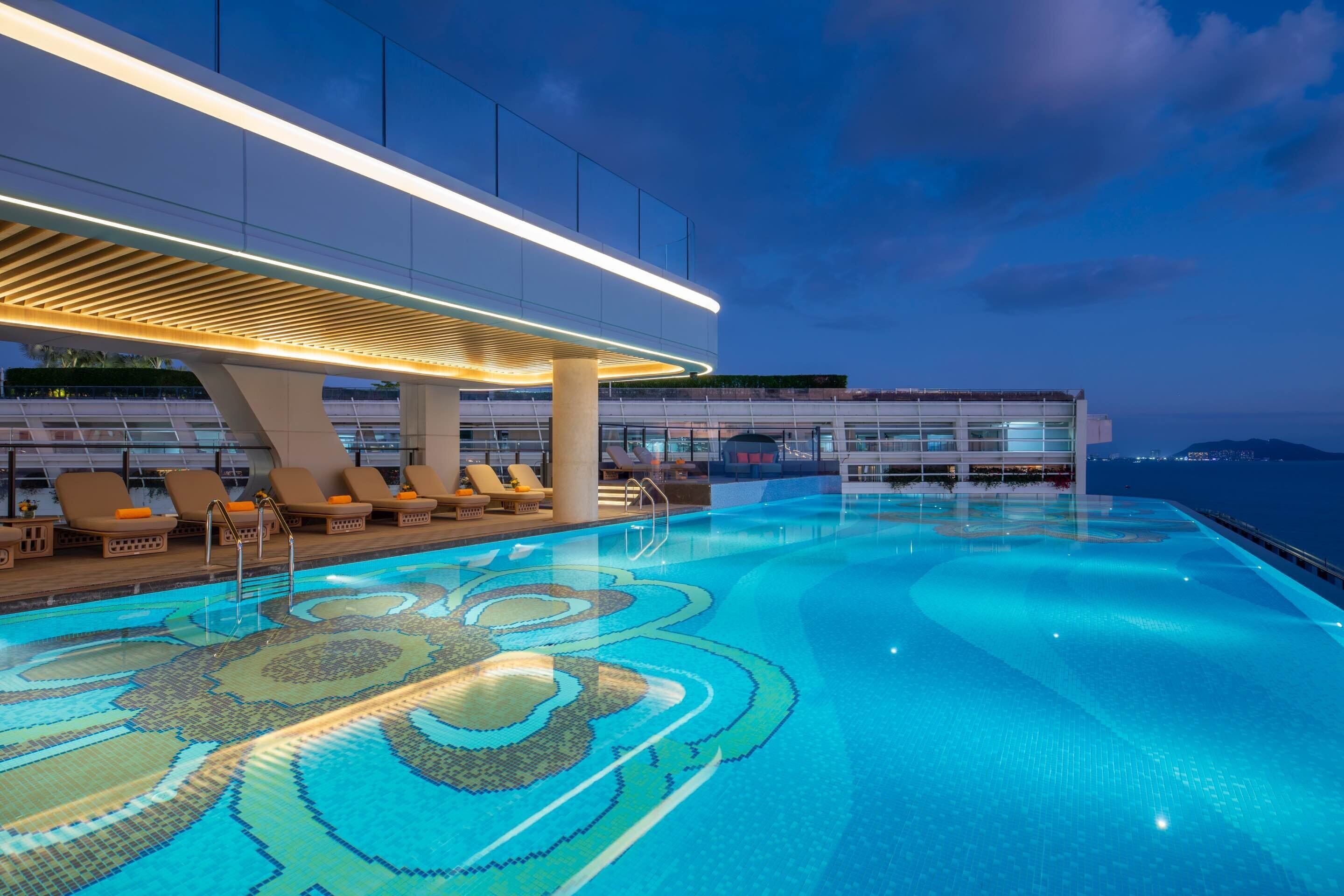 Una piscina al aire libre, sombrillas, sillones reclinables de piscina