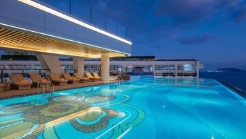 Una piscina al aire libre, sombrillas, sillones reclinables de piscina