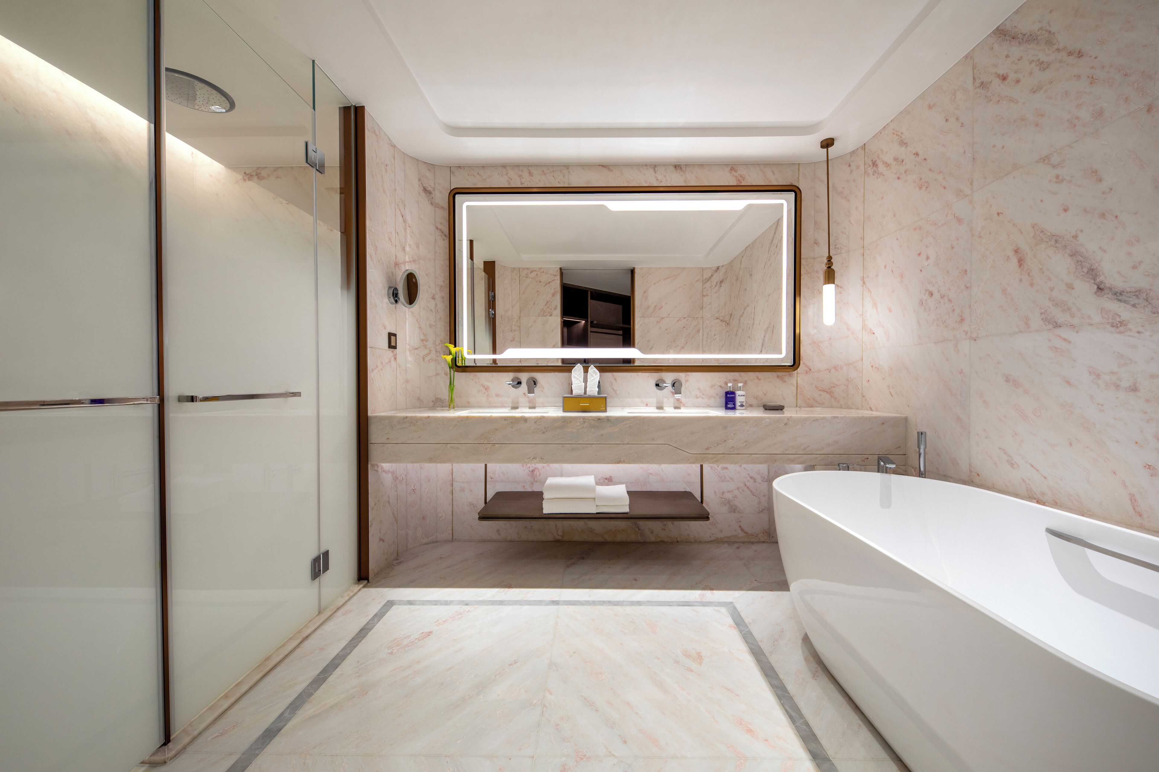 A modern bathroom with a glass shower enclosure, a freestanding bathtub, and a vanity with a mirror.