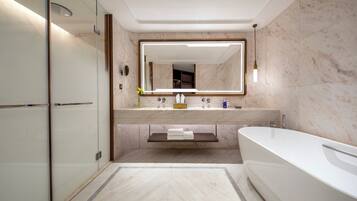 A modern bathroom with a glass shower enclosure, a freestanding bathtub, and a vanity with a mirror.