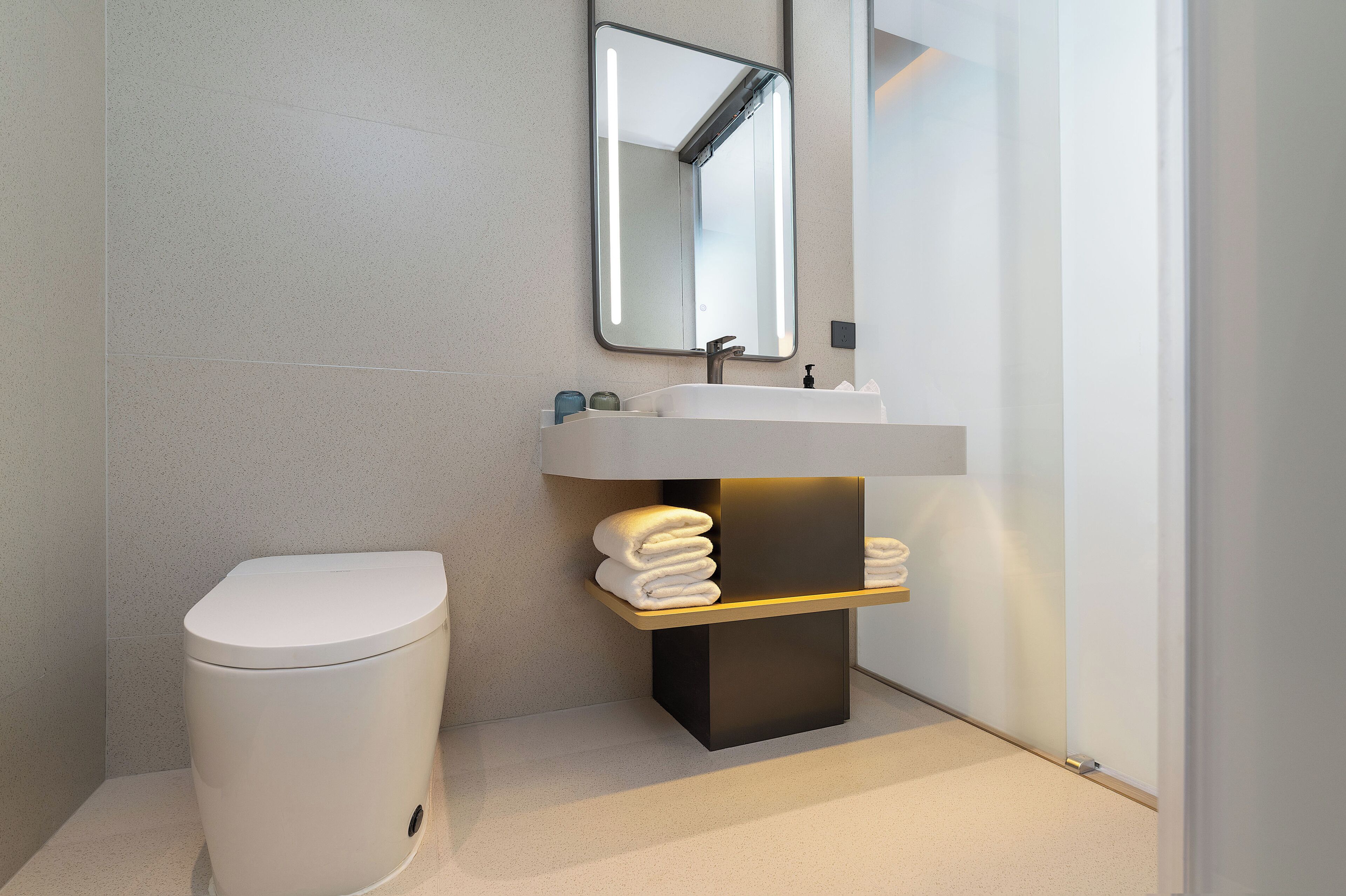 A modern bathroom with a toilet, a sink, and a mirror.