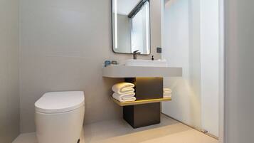 A modern bathroom with a toilet, a sink, and a mirror.